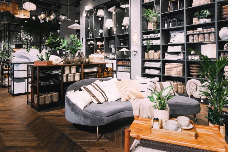 Home accessories and household products in store of shopping centre. View of home accessories for living room in shop fashion retail store. Sofa with pillows. View of assortment of decor for interior shop in store of shopping center